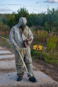 Military in protective suit checks radiation levels on the road dosimeter