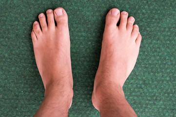 Fototapeta premium Selective focus. Male feet on green carpet.