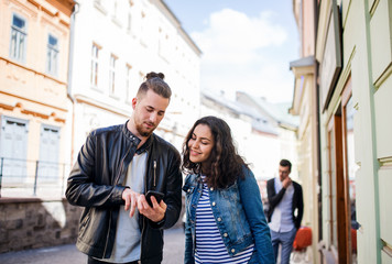 Young friends with smartphone standing outdoor in town, talking.