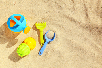 Fototapeta na wymiar Flat lay composition with plastic beach toys on sand. Space for text