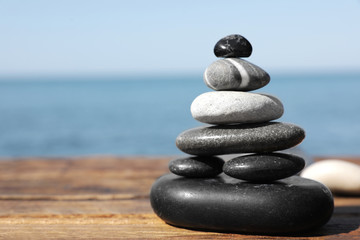 Stack of stones on wooden pier near sea seascape, space for text. Zen concept
