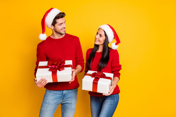 Portrait of positive married people with brown hair get packages wear red pullover denim jeans isolated over yellow background