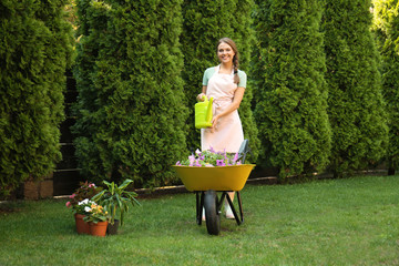 Happy young woman watering plants in garden