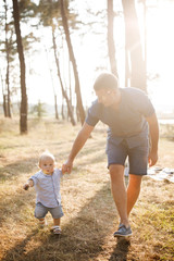 Fototapeta premium Young father walks with his cute little boy in a forest. Father's Day