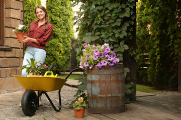 Female gardener with wheelbarrow and plants outdoors