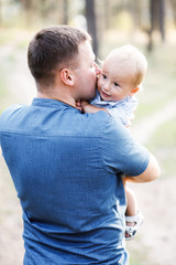 Young father walks with his cute little boy in a forest. Father's Day