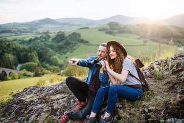 Fototapeta premium Young tourist couple travellers with binoculars hiking in nature, resting.