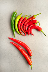 Hot spicy green and red pepper on a grey stone background .