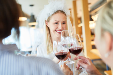  Frau mit Brautschleier beim Zuprosten mit Rotwein