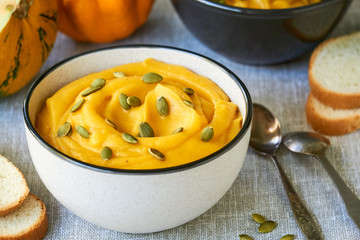 Thick pumpkin cream soup with seeds in a gray bowl 
