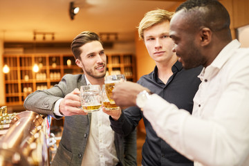 Männer prosten sich zu mit Bier am Tresen