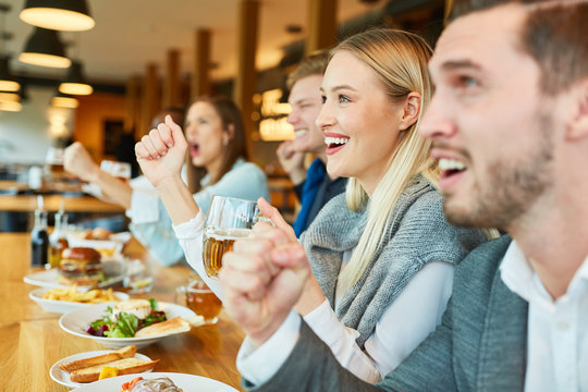 Sportfans am Tresen einer Bar schauen Spiel