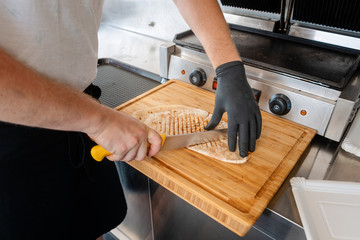 Chef cutting Mexican taco on wooden board