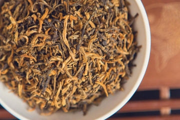 Chinese tea ceremony, Puer in assortment, Ceramic brown teapot for brewing tea and a bowl with raw materials on a bamboo table	
