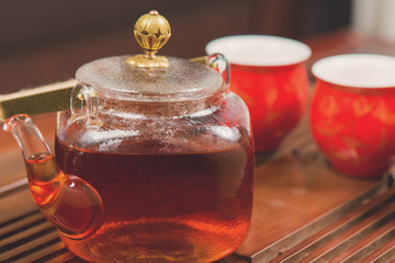 Chinese tea ceremony, Puer in assortment, Ceramic brown teapot for brewing tea and a bowl with raw materials on a bamboo table	