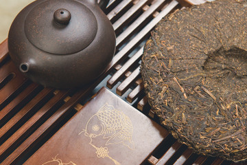 Chinese tea ceremony, Puer in assortment, Ceramic brown teapot for brewing tea and a bowl with raw materials on a bamboo table	