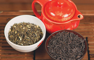 Chinese tea ceremony, Puer in assortment, Ceramic brown teapot for brewing tea and a bowl with raw materials on a bamboo table	