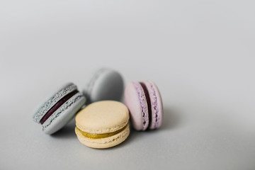 Closeup of sweet macaroon biscuits of pastel color lying in a pile on light grey background. Copy space.