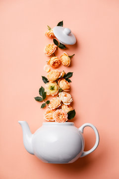 Creative layout made of whte tea pot with orange roses on pink background