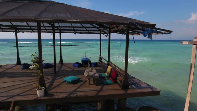 dream holiday public beach terrace, wooden pier platform with balinese seating, amazing sea view, shot from moving drone, gili trawangan, bali, indonesia