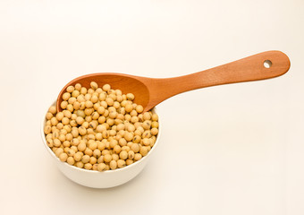 Soybeans on spoon in a wooden bowl isolated on a white background.