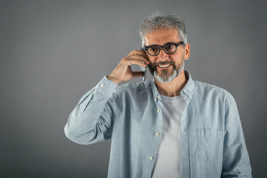 mid aged gray haired man using cell phone isolated on gray background