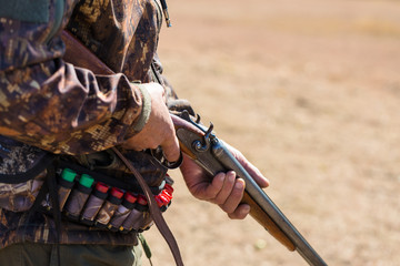 Close up of hunter loading shotgun,  holds a gun and ammunition in his hand.