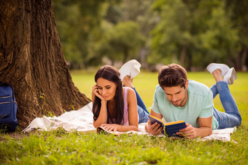 Her she his he nice attractive lovely smart clever focused concentrated best friends spending weekend free spare time on fresh open air lying under tree on veil cover outside