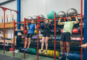 Group of athletes doing pull ups in the gym