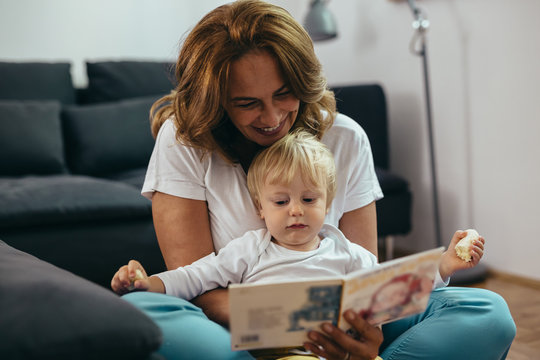woman with her grandson reading picture book at home