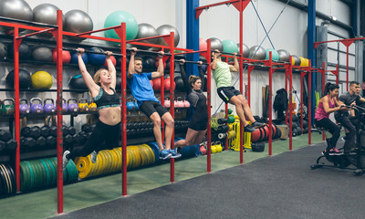Group of athletes doing pull ups and air bike in the gym