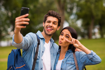 Photo of carefree mood pair using telephone making selfies with v-sign symbol wear casual denim outfit