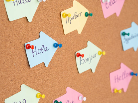 Learning Foreign Language concept. Handwritten Flashcards with Hello in other languages pinned on a cork board. Selective focus