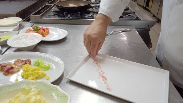 Chef sta posizionando sale grosso rosa e un filetto di manzo con carote in un piatto