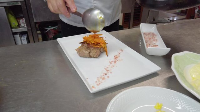 Chef sta posizionando sale grosso rosa e un filetto di manzo con carote in un piatto