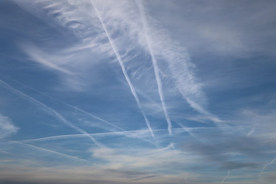 Background with white contrails of airplanes in the blue sky, copy space