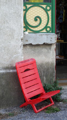 Fototapeta na wymiar Old red plastic children's chair in front of the flea market's entrance