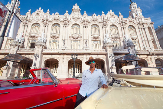 Taxi driver next to his vintage car in front of the Gran Teatro de La Habana, Havana, Cuba