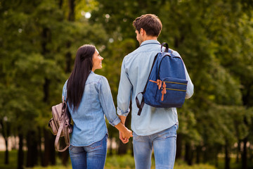 Fototapeta premium Behind view photo of cute pair groupmates walking dormitory hostel after lessons hold arms wear denim outfit