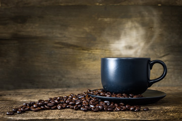 Cup of hot coffee and coffee beans on old wood background