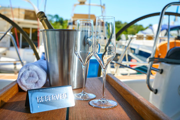 Romantic luxury evening on cruise yacht with champagne setting. Empty glasses and bottle with champagne and tropical sunset with sea background