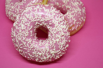 Donuts with icing on pastel pink background. Sweet donuts.