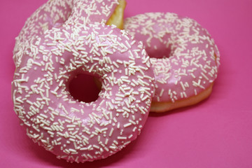 Donuts with icing on pastel pink background. Sweet donuts.