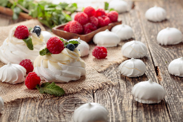 Dessert Pavlova with raspberries, blueberries and mint on a old wooden table.