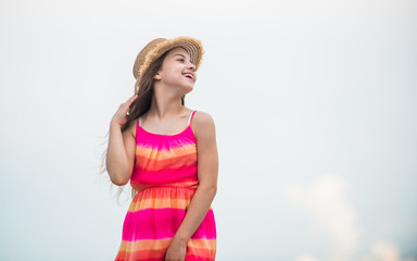 Enjoying relax. Child happy small girl. Free and carefree. Good vibes. Happy international childrens day. Cute girl in summer dress and hat outdoors sky background. Happy vacation. Happy childhood