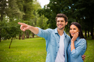 Portait of pretty man pointing with his index finger and shocked woman with brunette hair touch her cheek scream wear denim jeans shirt outdoors