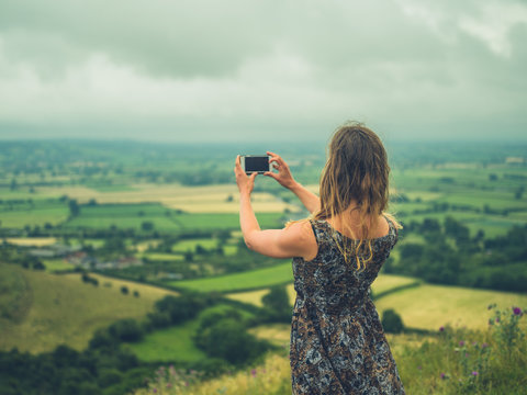 Young woman taking photos with smartphone in nature