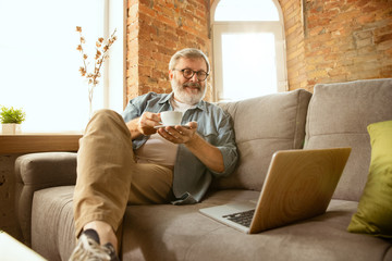 Senior man working with laptop at home - concept of home studying. Caucasian male model sitting on...