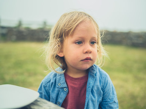 Little toddler sitting at picnic table outside