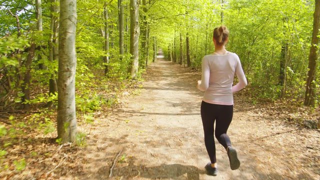 Woman Running On Forest Path